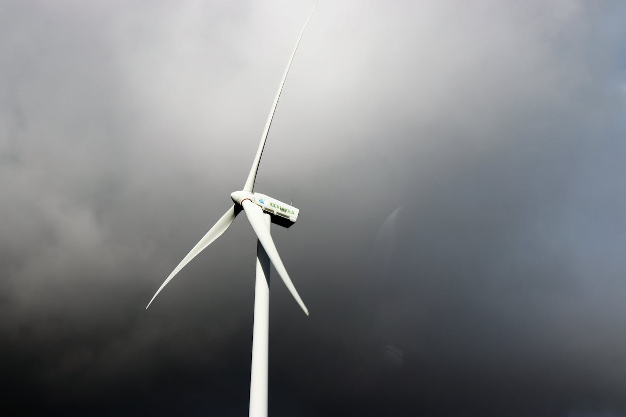 A wind turbine stands tall against a backdrop of dark, stormy clouds, symbolizing clean energy.